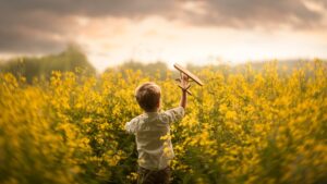 Child-little-boy-play-toy-plane-in-the-rapeseed-flowers-field_1920x1080